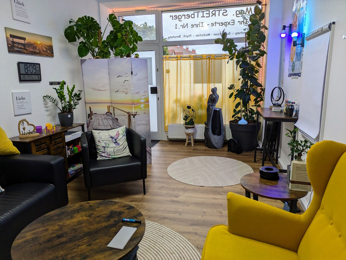 Innenansicht der Praxis mit Sofa, Ohrenstuhl, Pflanzen etc