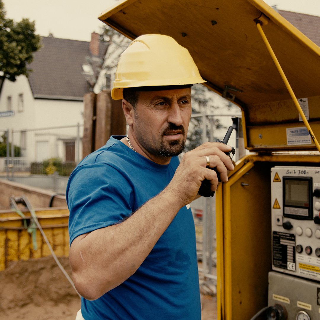 Bauarbeiter mit Helm spricht in Walkie Talkie