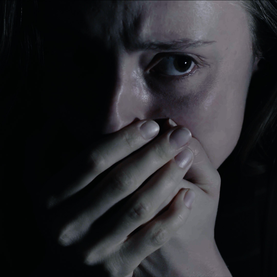 Frau schaut ängstlich und hält sich den Mund zu