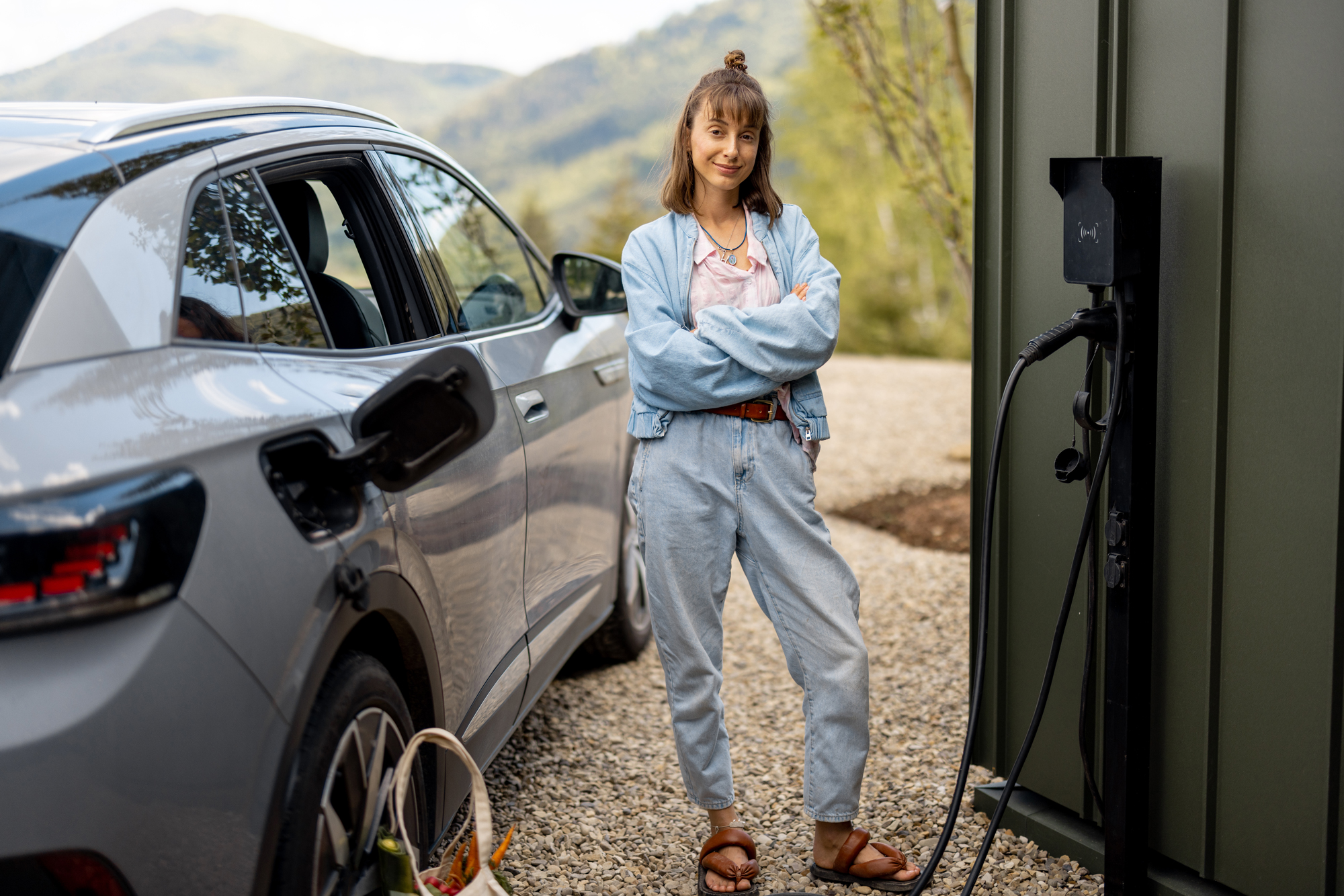 Eine Frau steht neben einem E-Auto beim Laden an einer Wall-Box - einfach, sauber, umweltbewusst - eMobil Stadtwerke Stendal GmbH für private und gewerbliche  Kunden in der Region Altmark, Sachsen-Anhalt