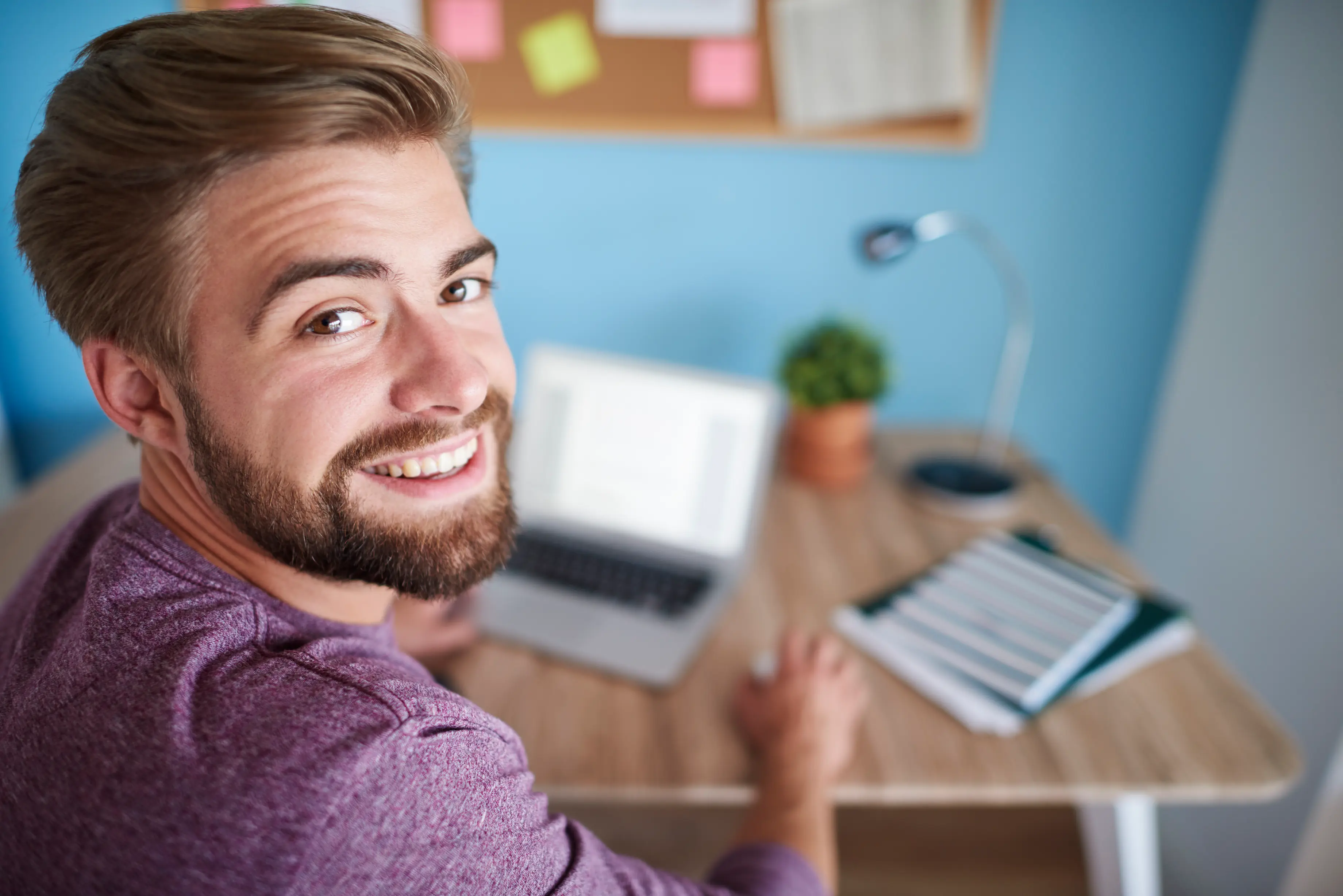 Bewerber am Laptop freut sich und lächelt in Kamera