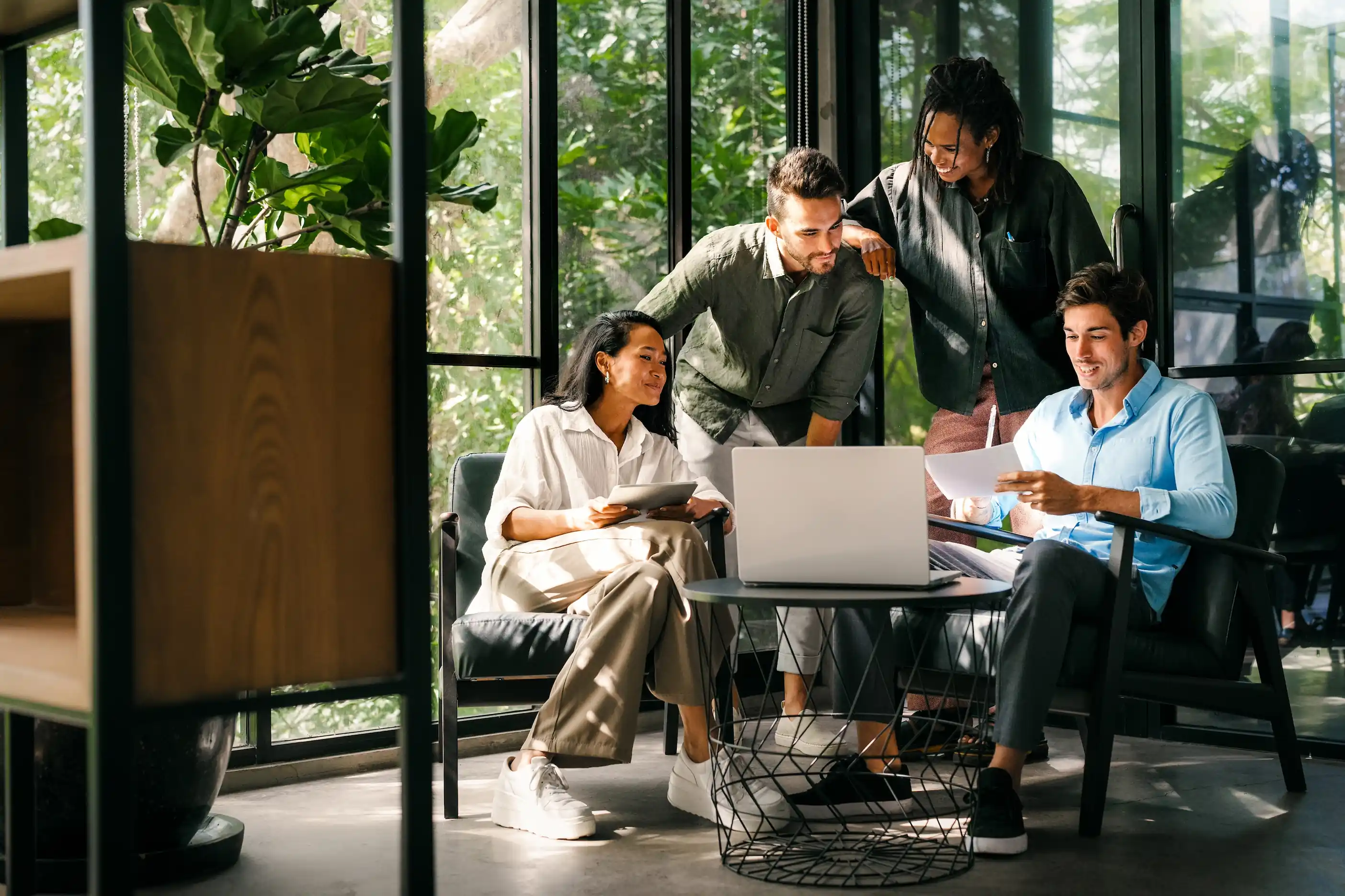Team im Büro arbeitet zusammen an einem Laptop