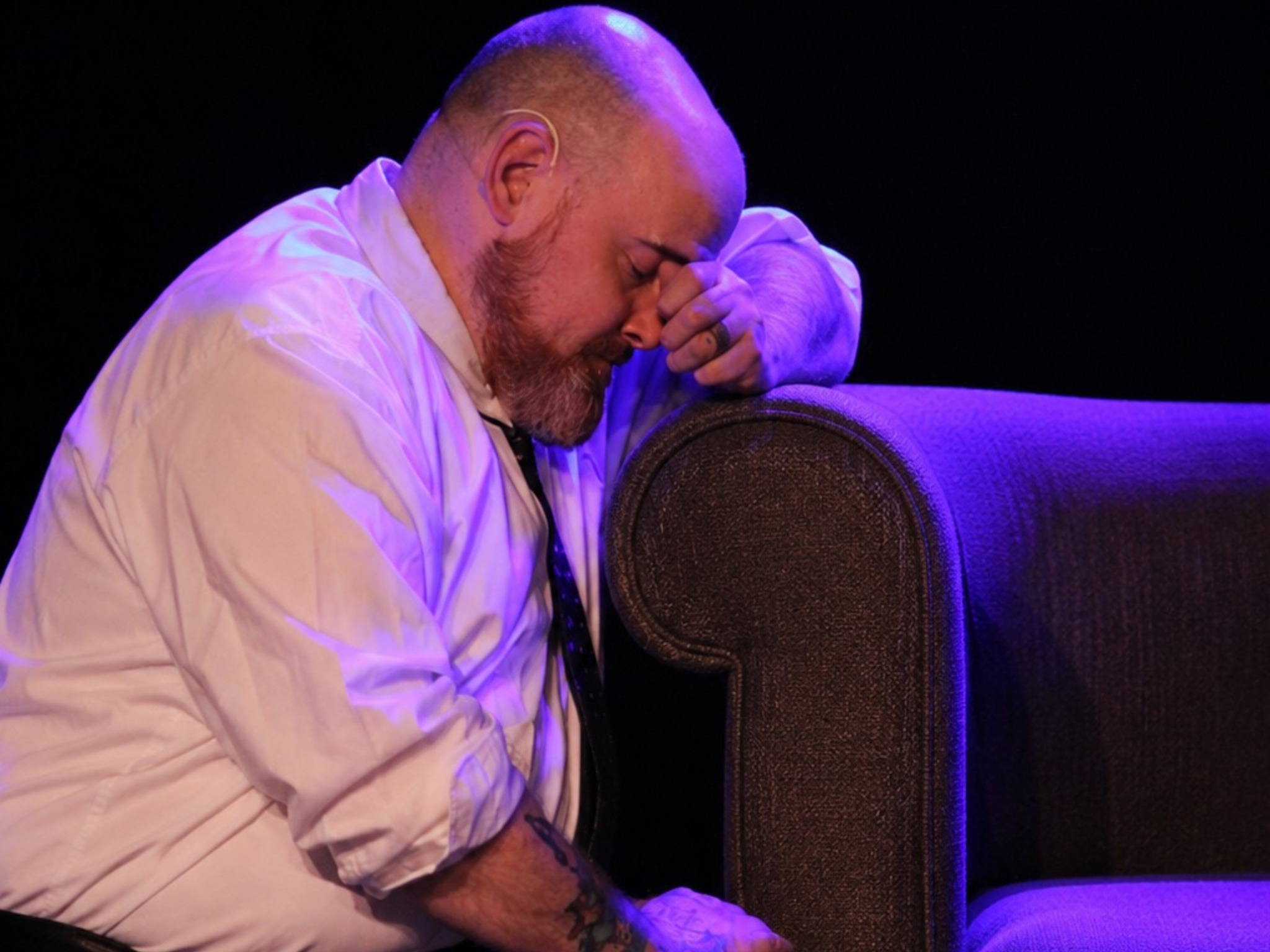 Chris Duke kneeling in distress against a sofa during a scene from 1 Missed Call