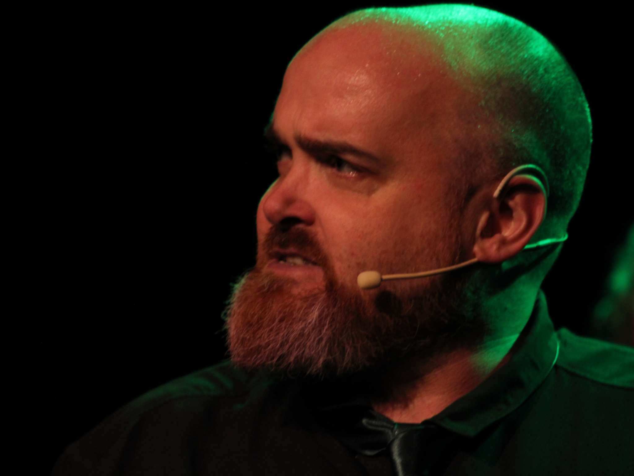 Close-up of Chris Duke bathed in green stage lighting