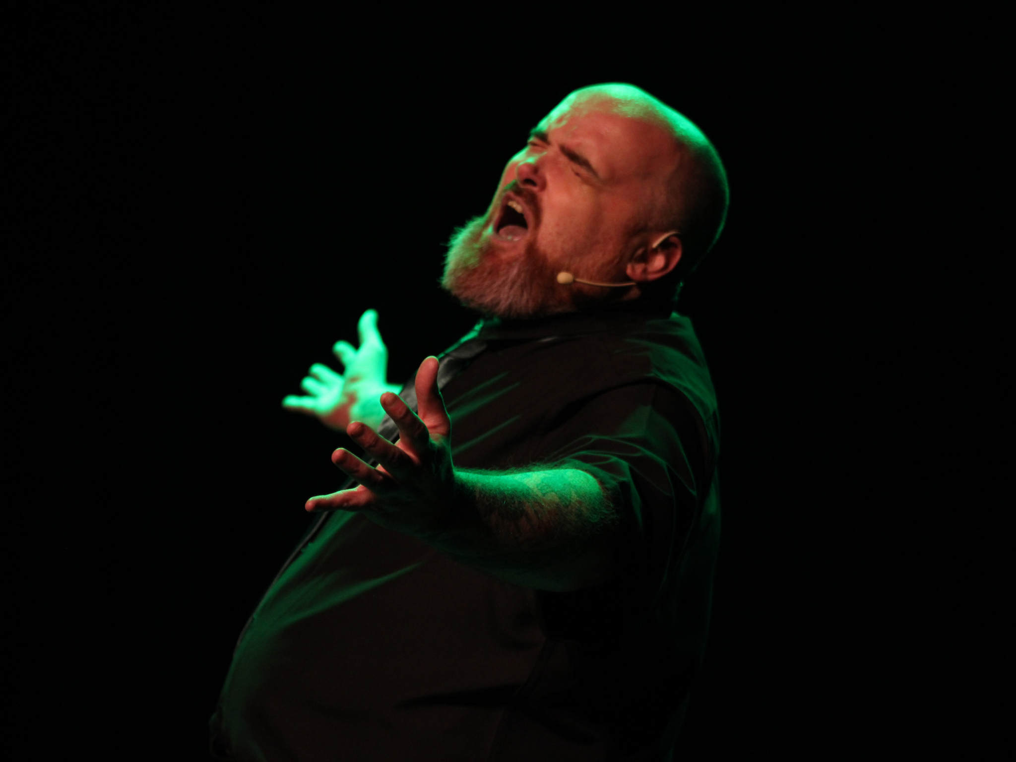 Chris Duke singing passionately with arms outstretched on stage