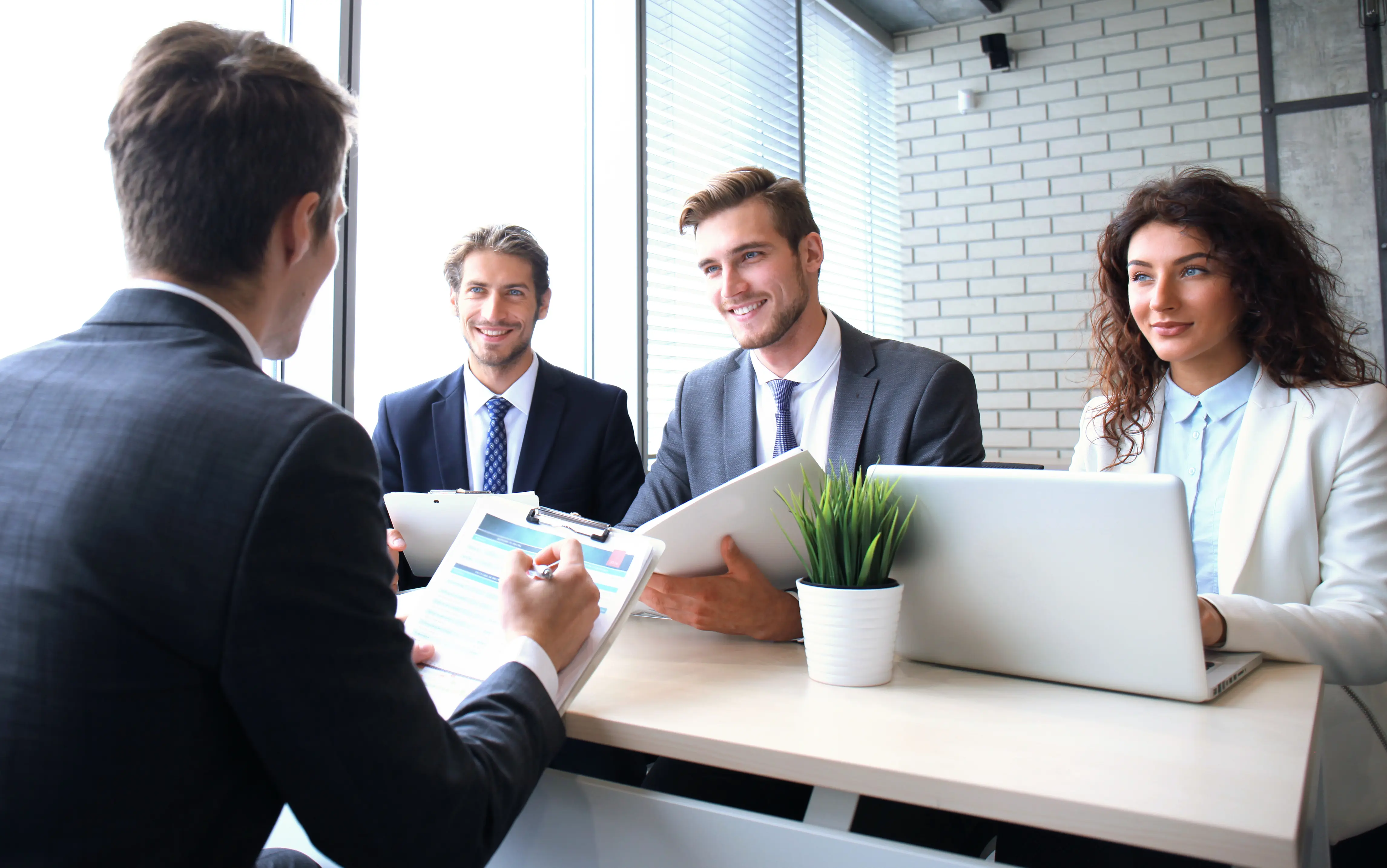 Personalberater im Gespräch mit drei Bewerbenden während eines Vorstellungsgesprächs in einem modernen Büro.