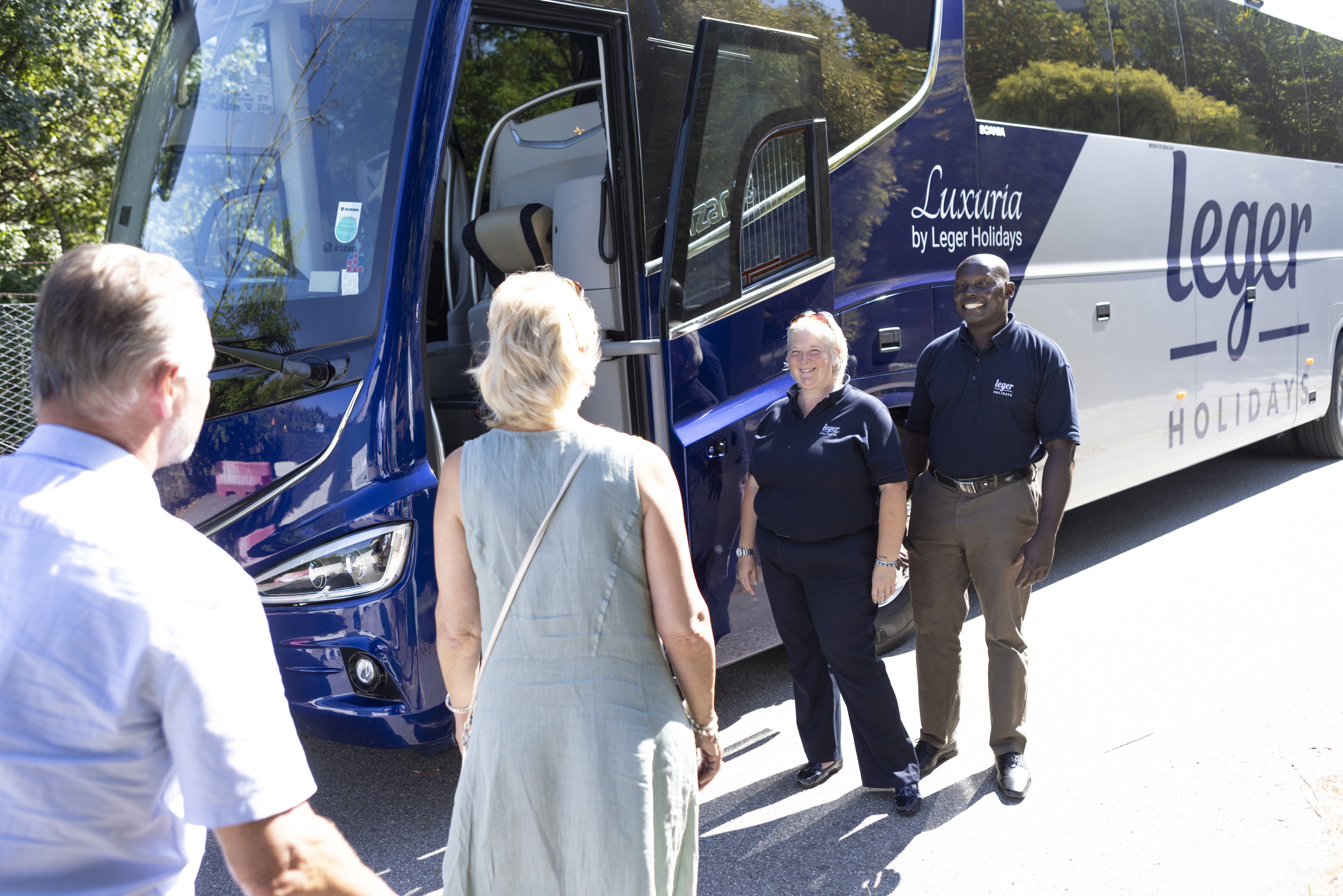 Employees greet a women onto her coach