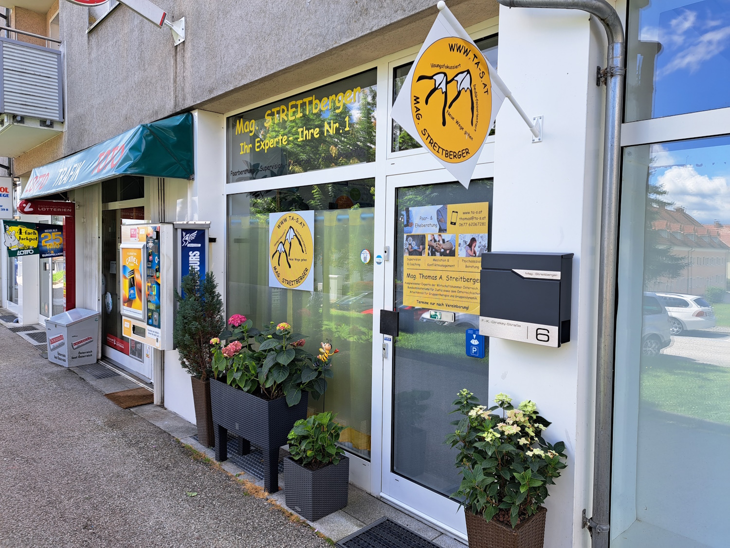 Außenansicht der Praxis. Man sieht Blumen davor.