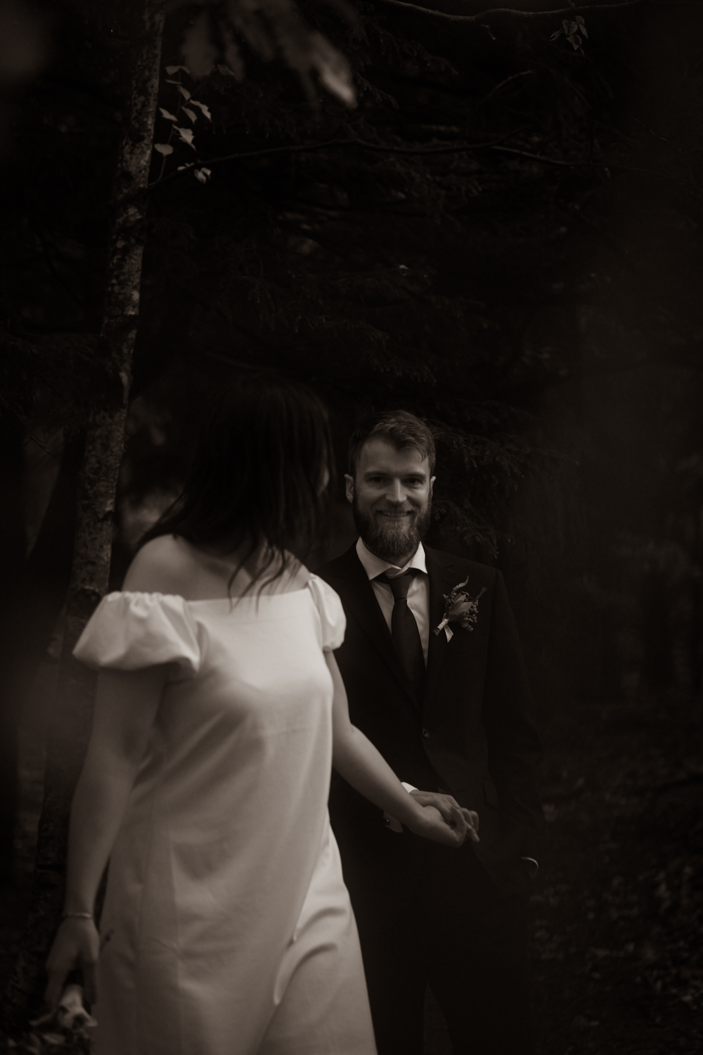 Dokumentär bröllopsfotografering i Göteborg. Svartvit bild på brudpar som håller handen och går i skogen.