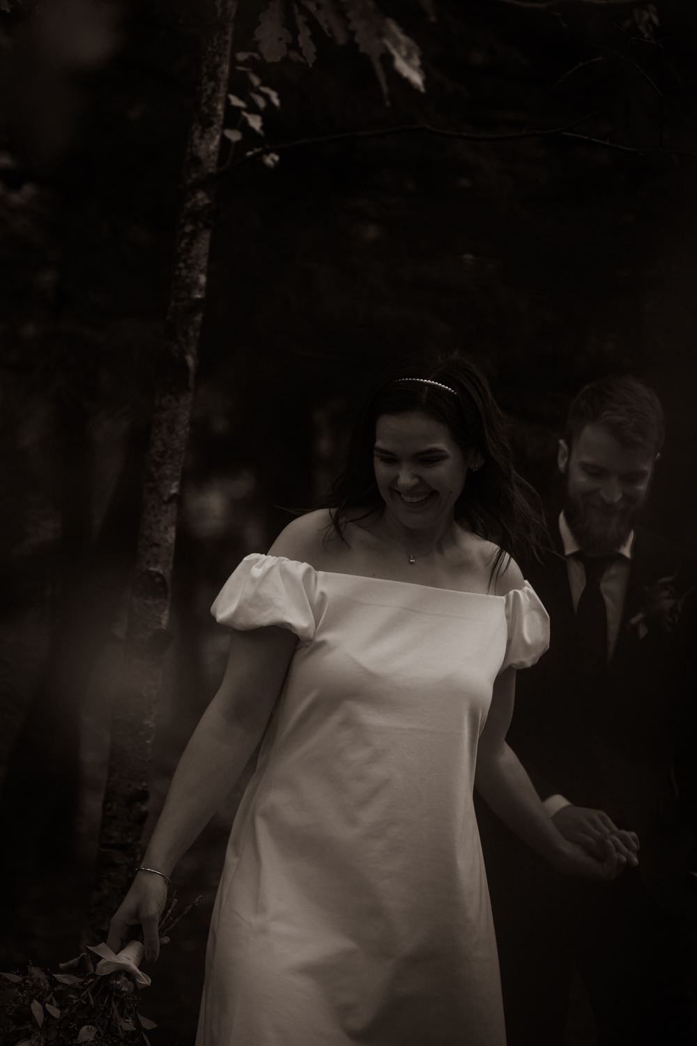 Höstbröllop i Göteborg dokumenterat av bröllopsfotograf Therese Alfredsson. Brudpar som skrattar och går i skogen i svartvitt porträtt.