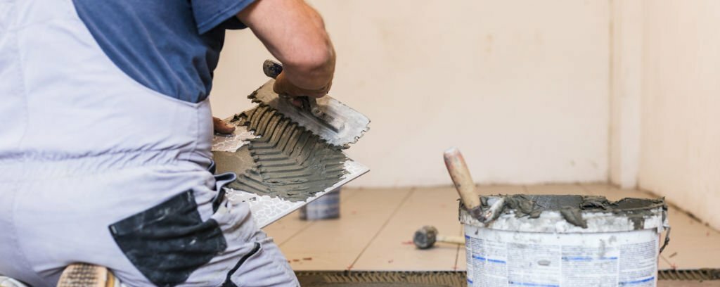 Fachmann verlegt Fliesen in einem Badezimmer – All-Around-Handwerker Berlin