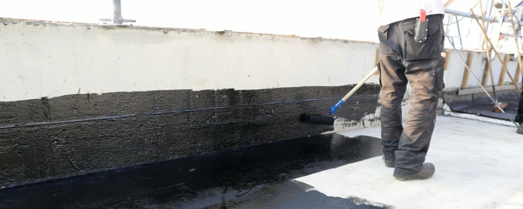 Handwerker trägt Abdichtung auf eine Hauswand auf – All-Around-Handwerker Berlin