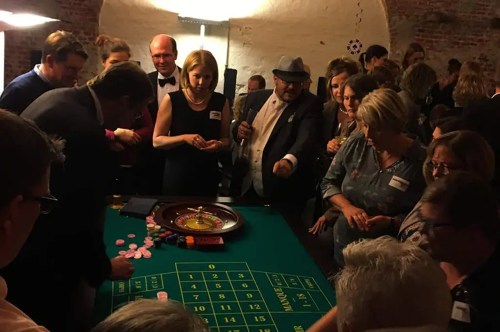 Gäste in festlicher Kleidung am Roulette-Tisch im Gewölbekeller