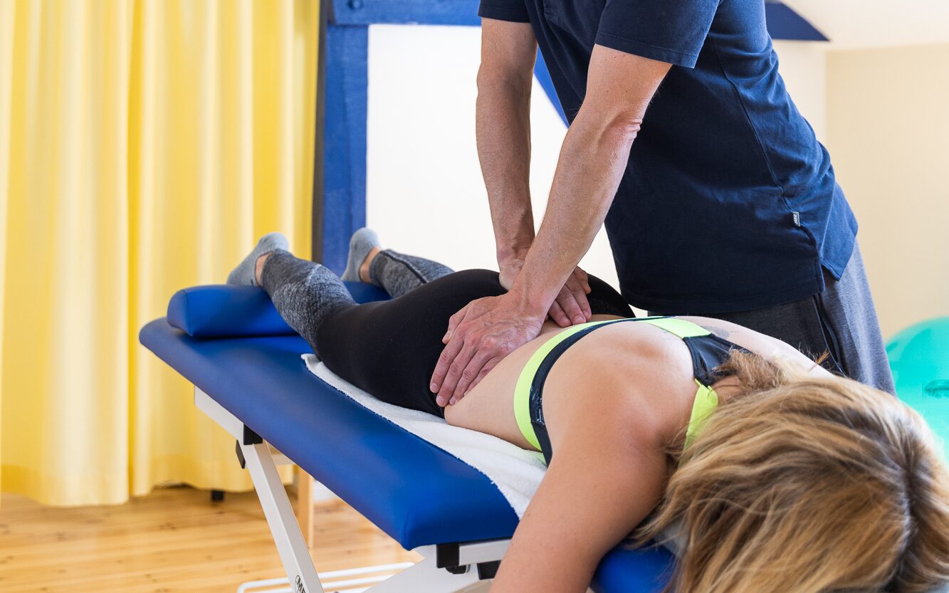 Manuelle Therapie am Rücken einer Patientin