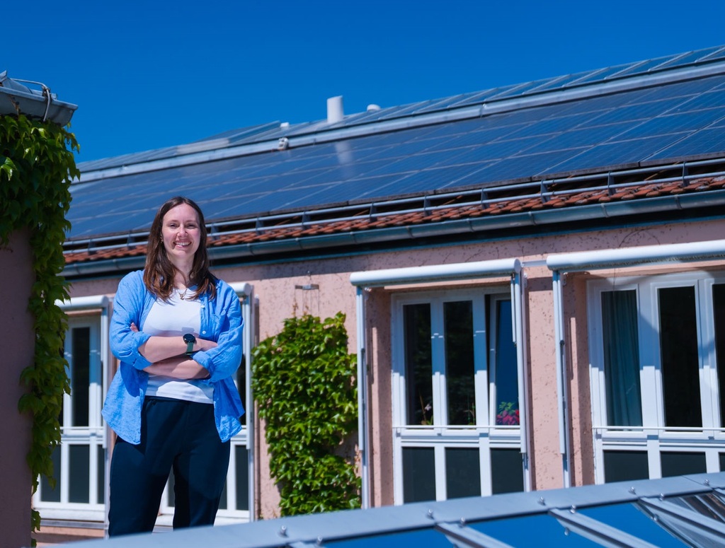 Klimaschutz in Garching – Frau steht vor einem Gebäude mit Photovoltaikanlage