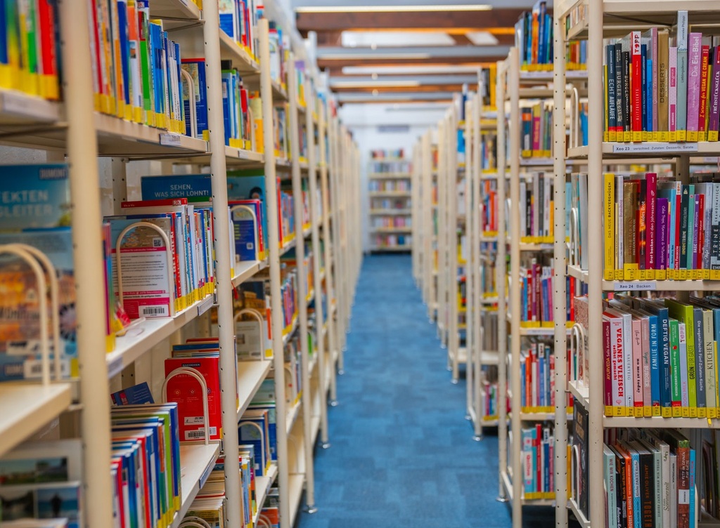 Blick durch einen Gang zwischen hohen Bücherregalen