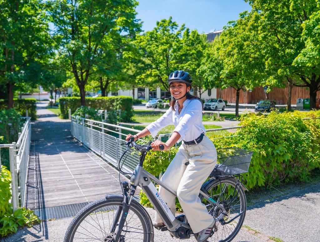 Radverkehr in Garching – Frau mit Helm auf städtischem Leihfahrrad überquert eine Brücke