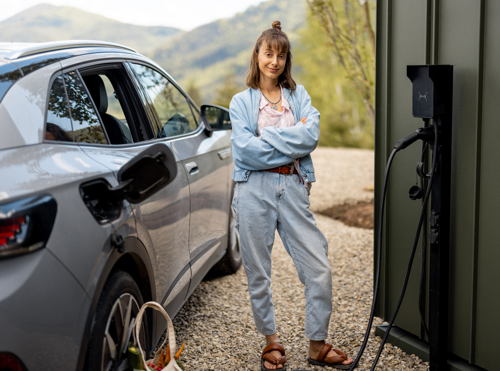 Eine Frau steht neben einem E-Auto beim Laden an einer Wall-Box - einfach, sauber, umweltbewusst - eMobil Stadtwerke Stendal GmbH für private und gewerbliche Kunden in der Region Altmark, Sachsen-Anhalt