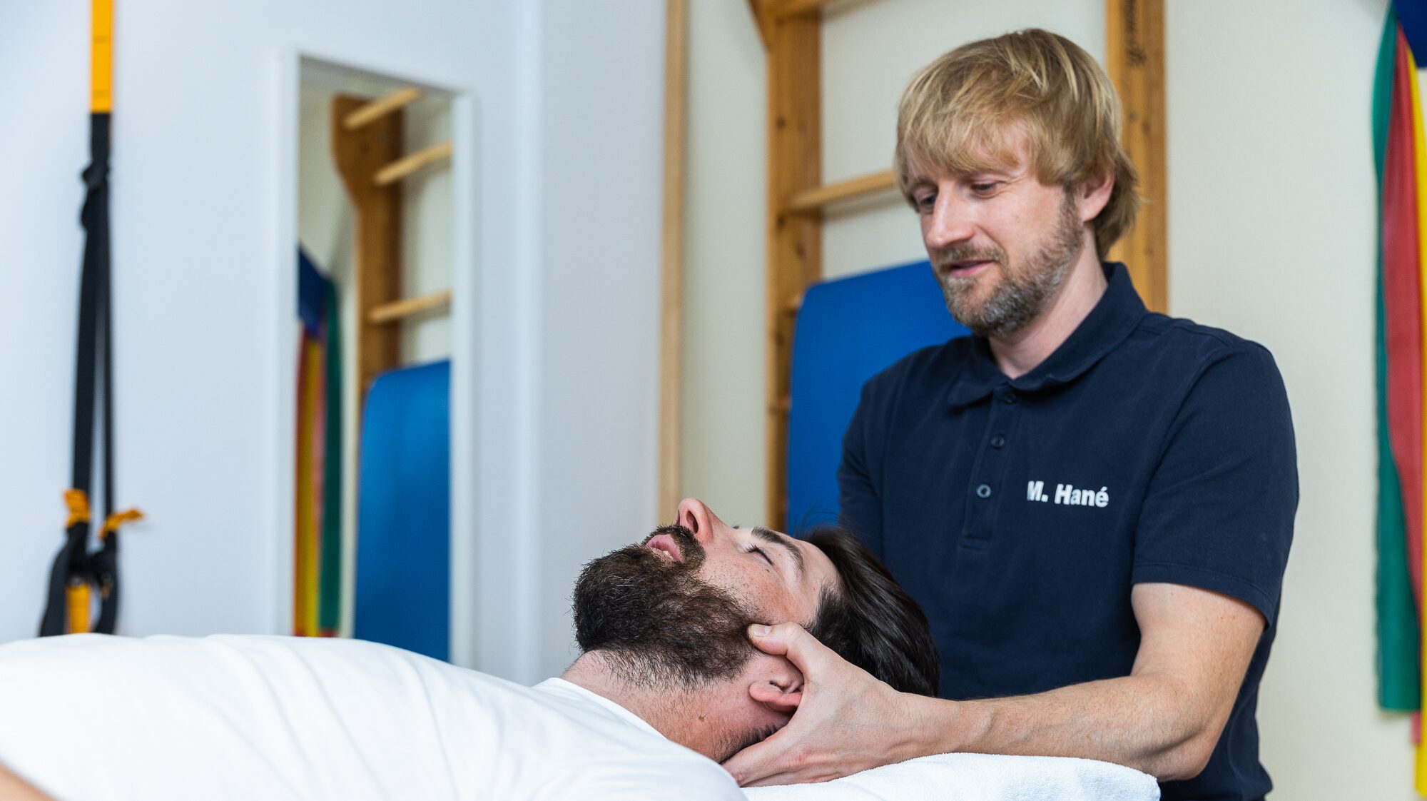  Physiotherapeut führt manuelle Therapie am Nacken und Kopf eines Patienten durch