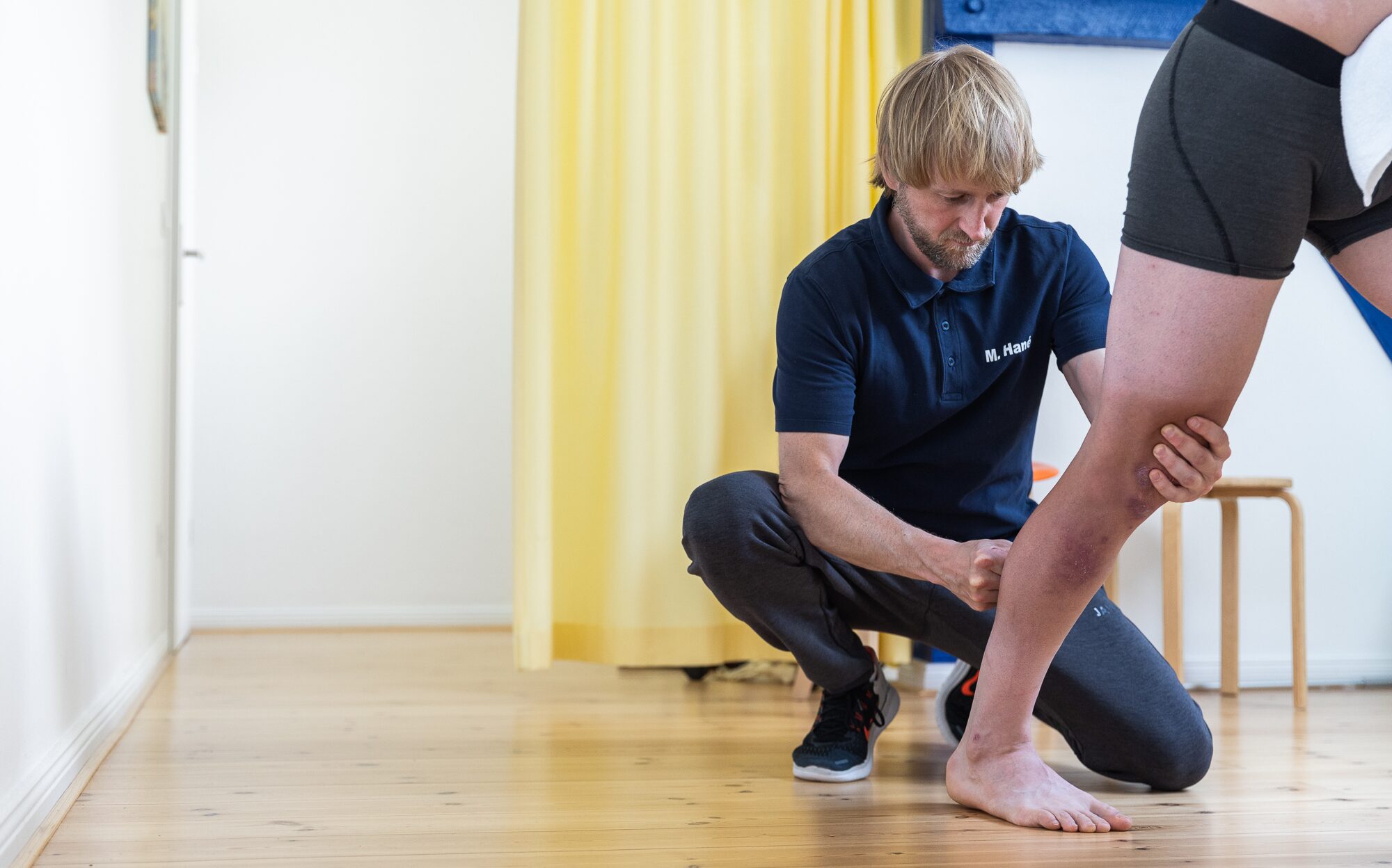 Physiotherapeut untersucht Sprunggelenk einer Patientin