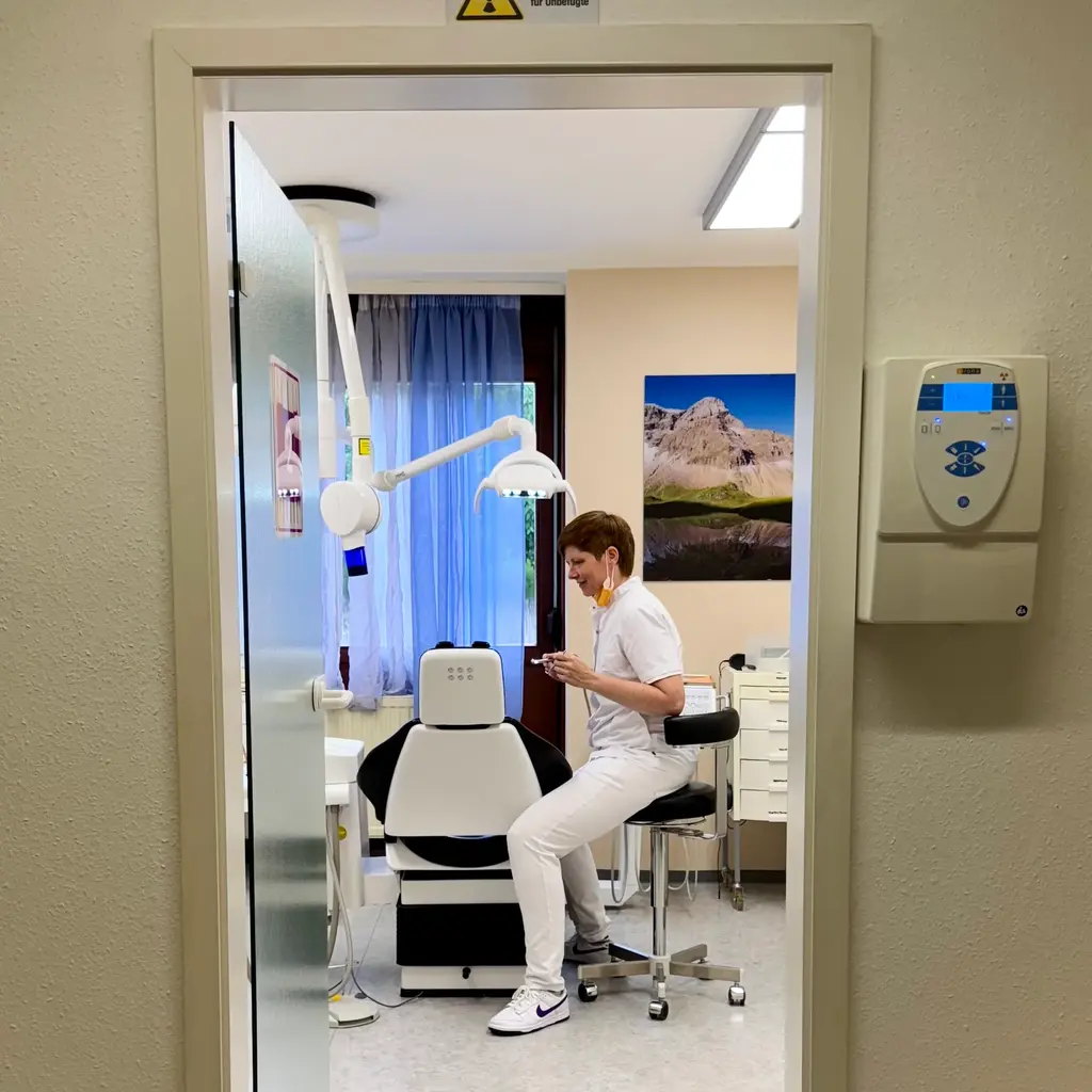 Zahnärztin auf Stuhl neben Patienten in Untersuchung