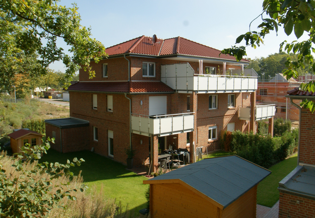 Wohnhaus mit rotem Ziegeldach und Balkonen an der Straßenecke