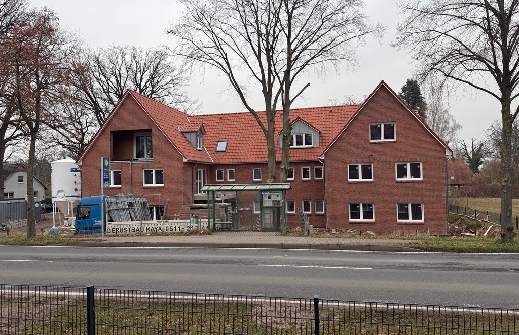 Mehrfamilienhaus im Bau mit Gerüst und Bäumen davor