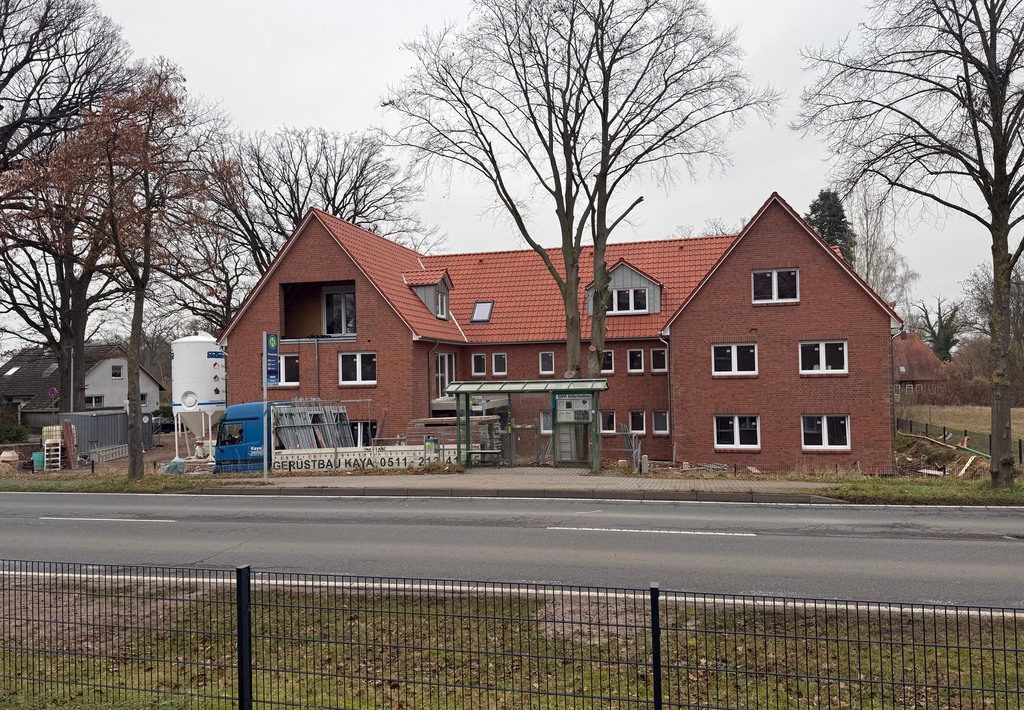 Wohnhaus mit rotem Ziegeldach und Balkonen an der Straßenecke