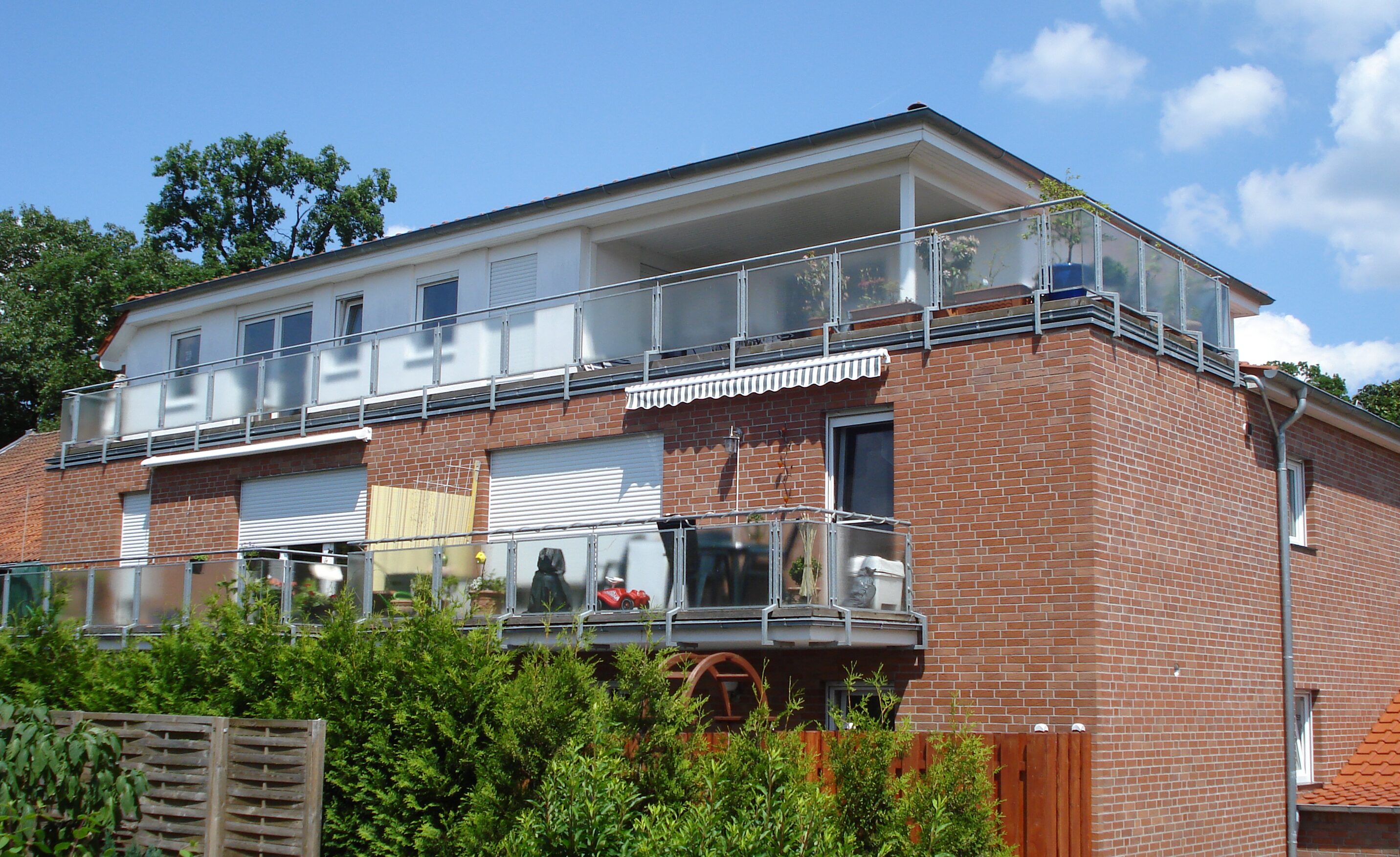 Mehrfamilienhaus mit zwei Balkonetagen und roter Klinkerfassade