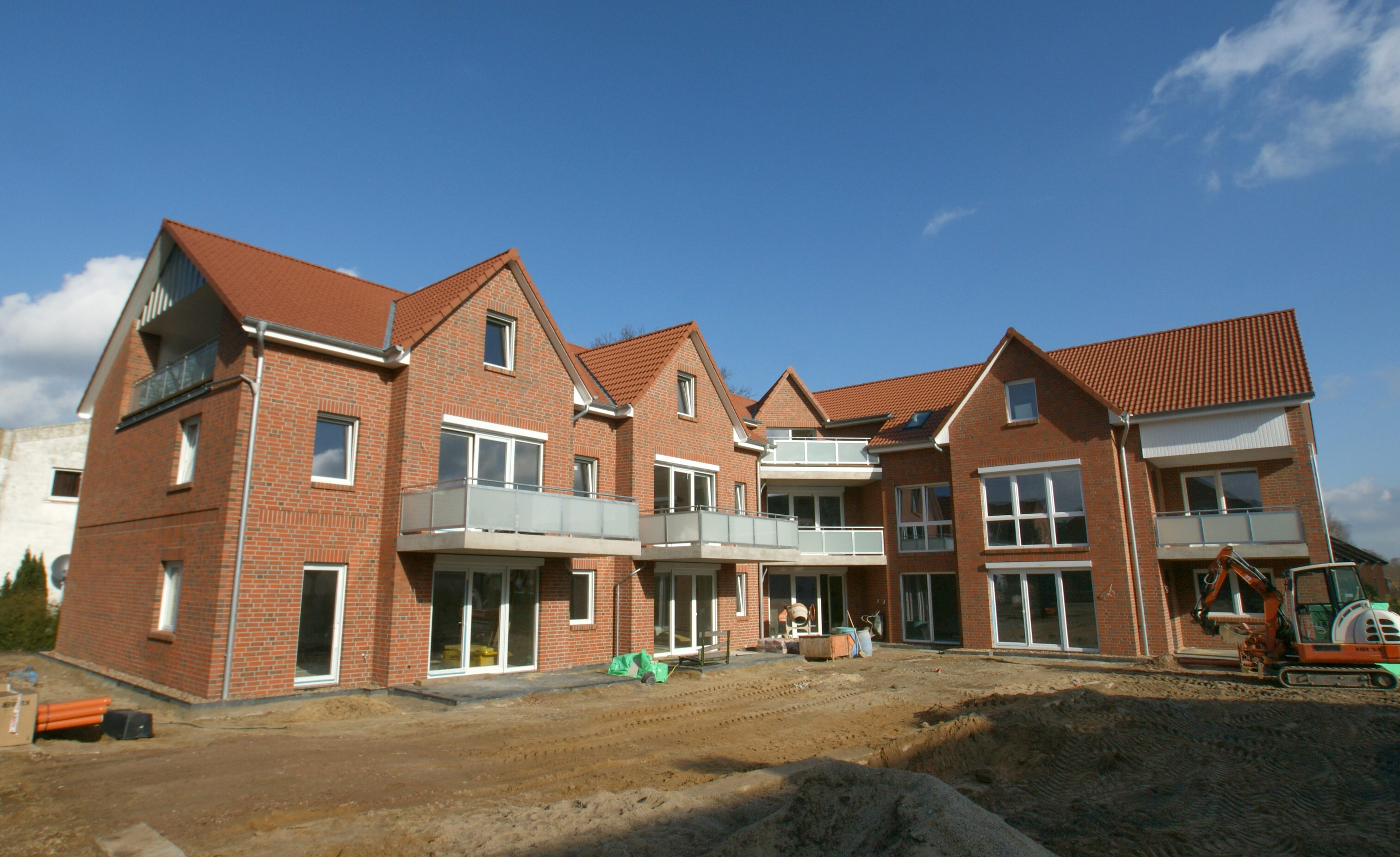 Mehrfamilienhaus mit roten Ziegeldächern und mehreren Balkonen