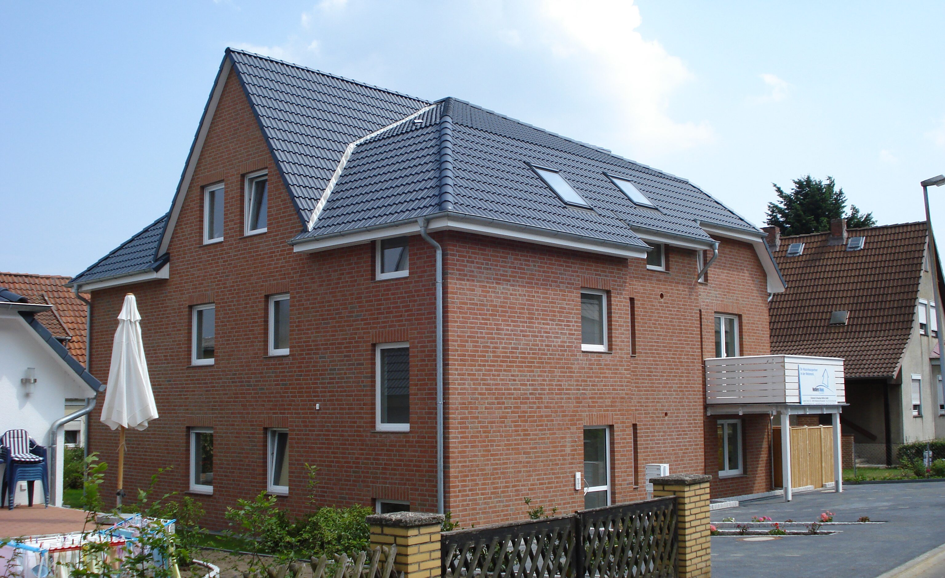 Wohnhaus mit dunkel gedecktem Dach und Balkon zur Straßenseite
