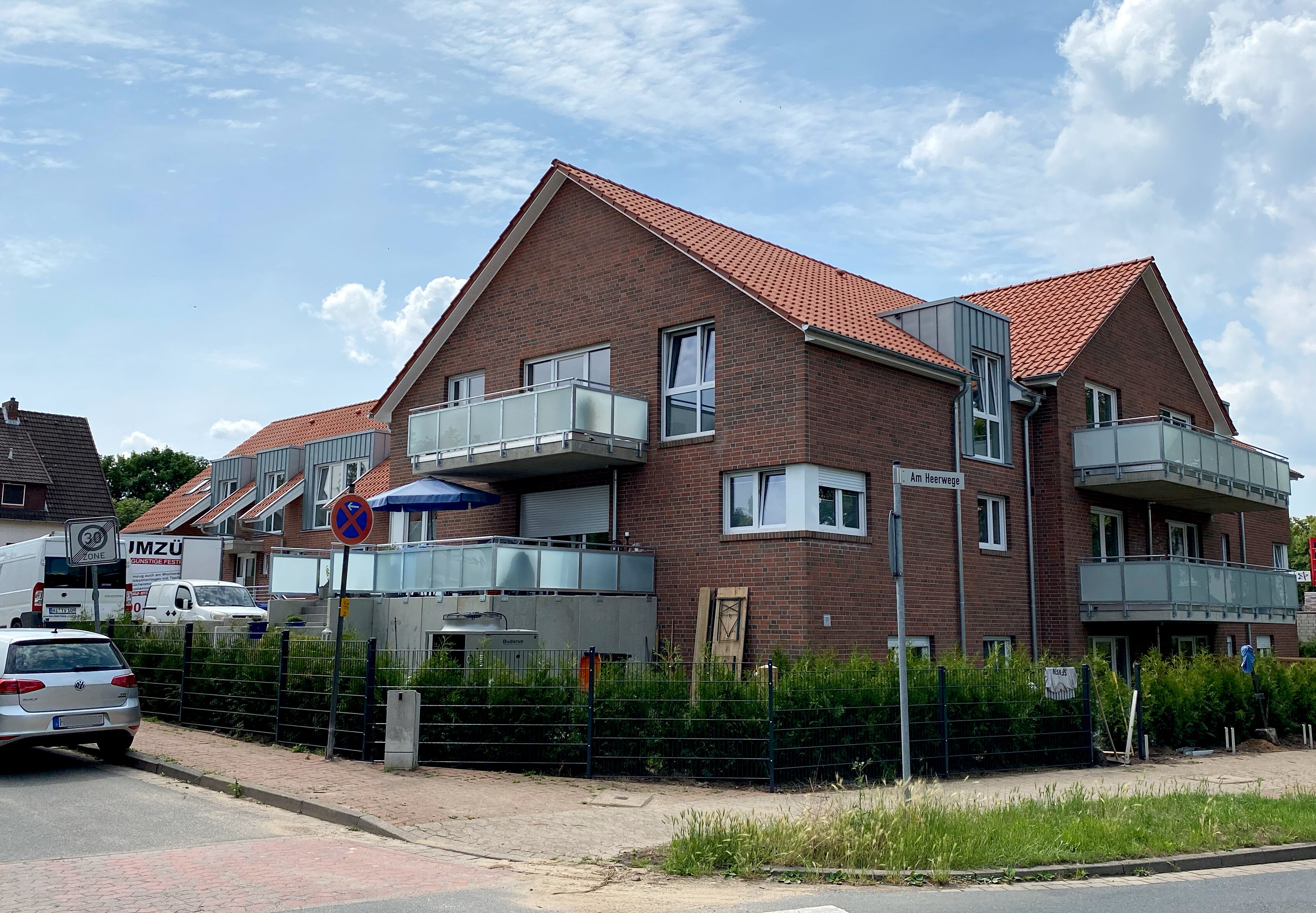 Wohnhaus mit rotem Ziegeldach und Balkonen an der Straßenecke