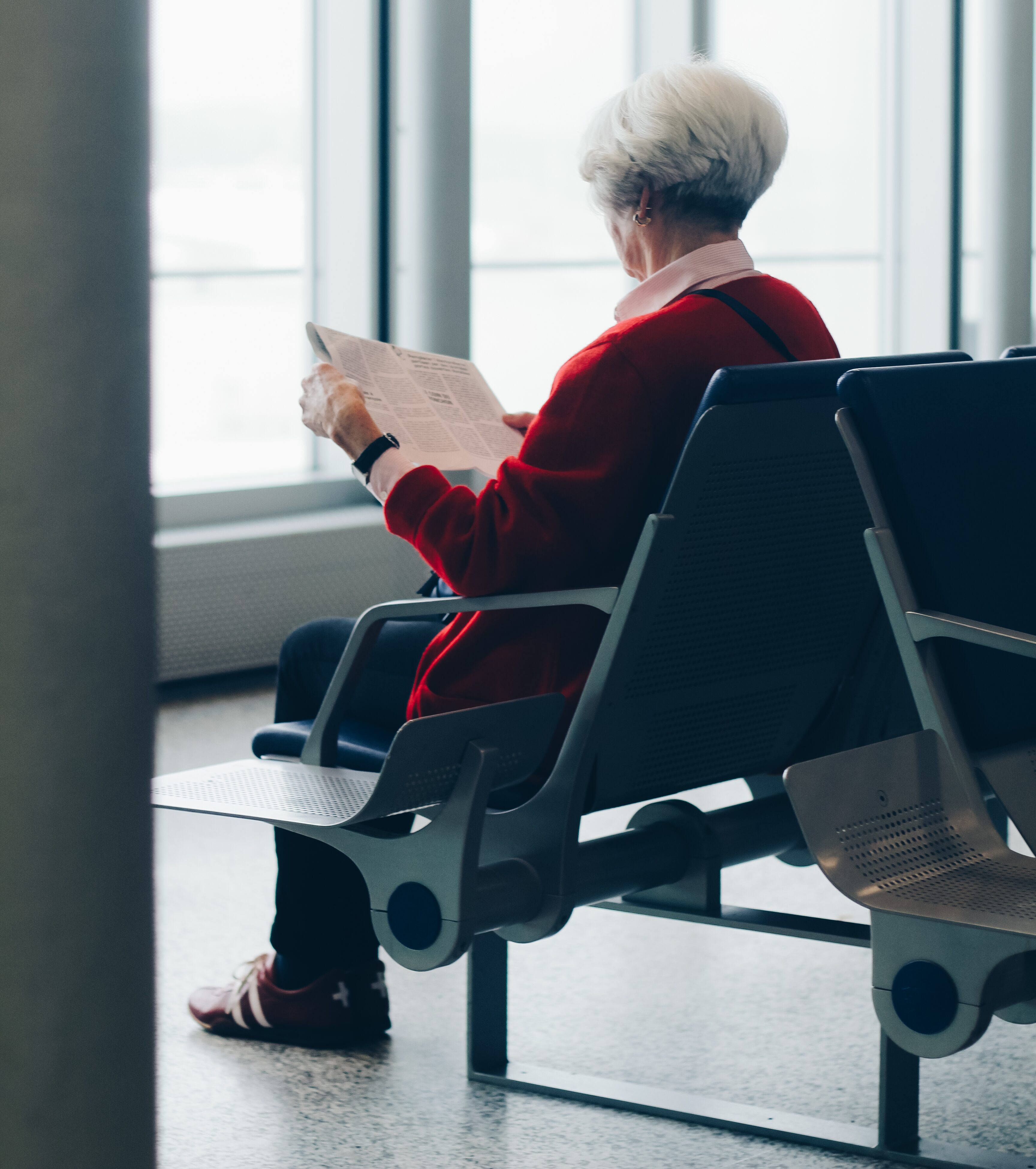 Woman in red cardigan reading paper at airport