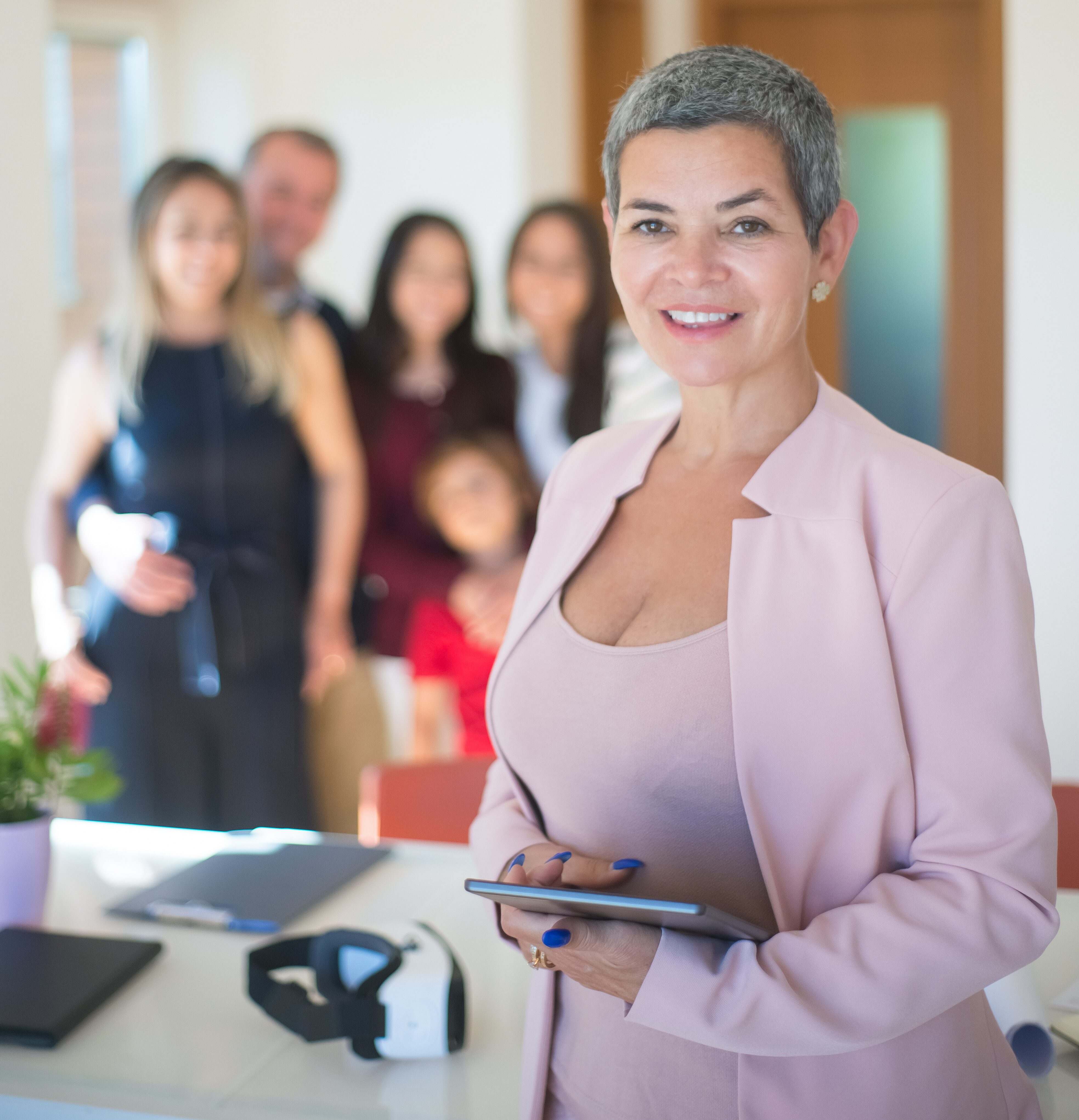 Businesswoman posing in front of team, holding tablet