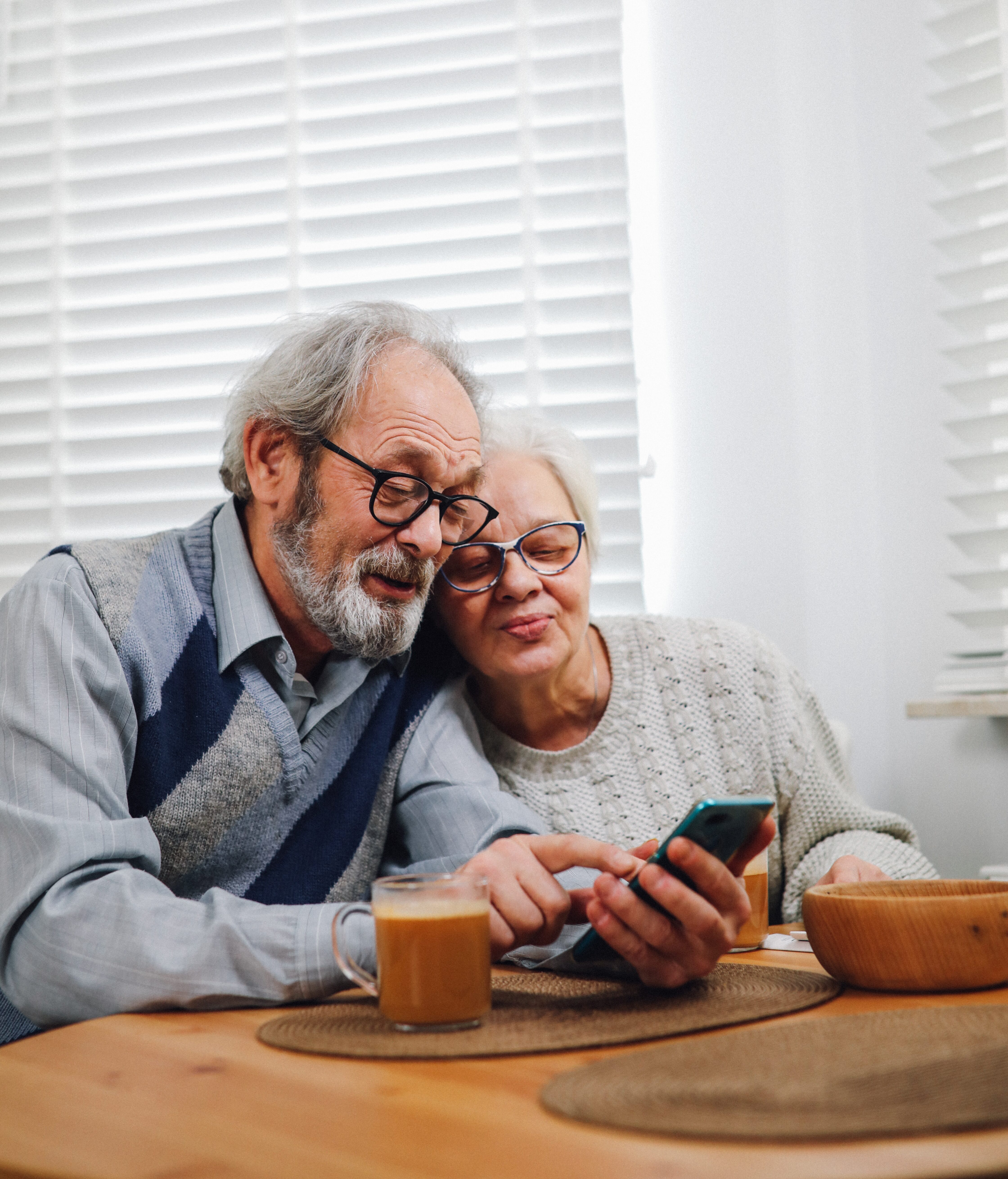 Older couple having coffee and working on smartphone