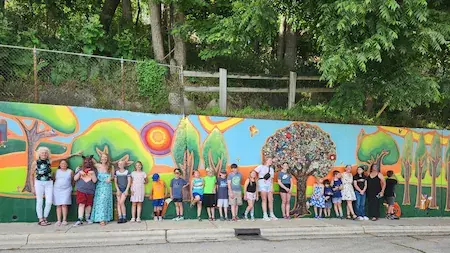 A group of people standing in front of a community mural