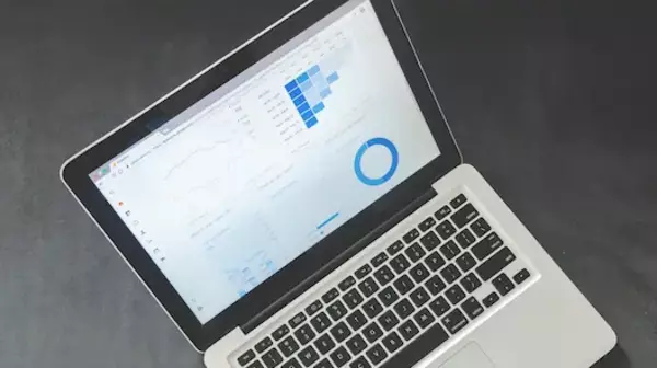 A macbook laptop open with a data dashboard on the screen
