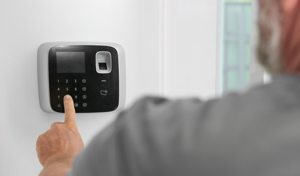 Mann, der Code auf der Tastatur des Alarmsystems in Innenräumen eingibt