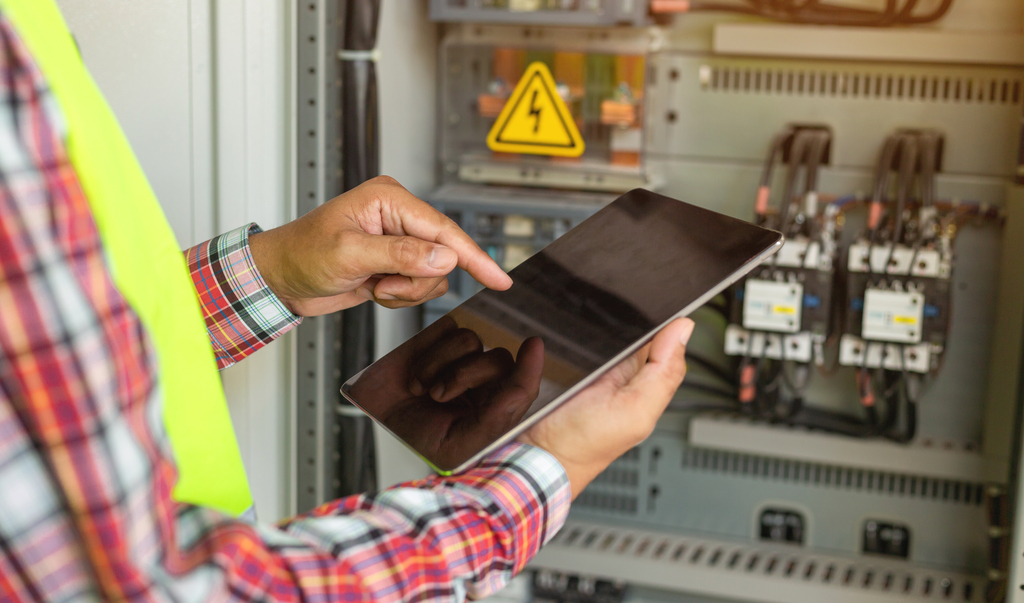 Stock-Foto ID: 1865613205 Nahaufnahme der Hand des Ingenieurs oder Elektrikers, der arbeitet, überprüft das elektrische System mit Tablet in der Fabrik.