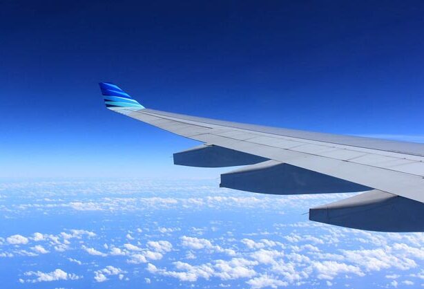 Foto aus einem Flugzeug heraus, man sieht Wolken und den Flügel