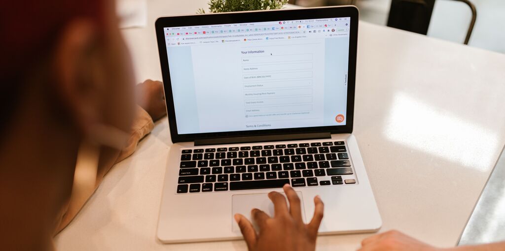 Eine Frau sitzt mit jemand weiterem vor einem Laptop, auf welchem eine Website mit einem Kontaktformular zu sehen ist.