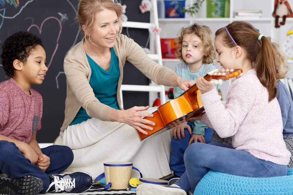 Prelude Music Team Placeholder image (woman giving a guitar to student)