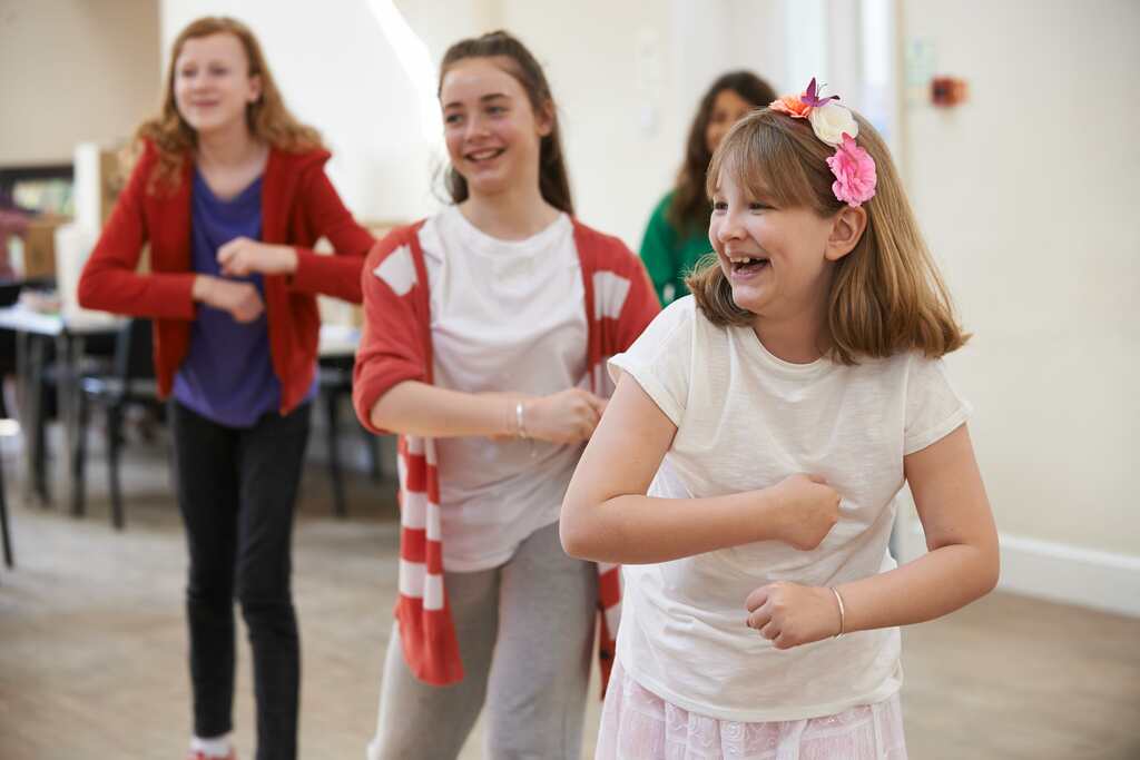 Young girls singing and dancing together in a musical theater class