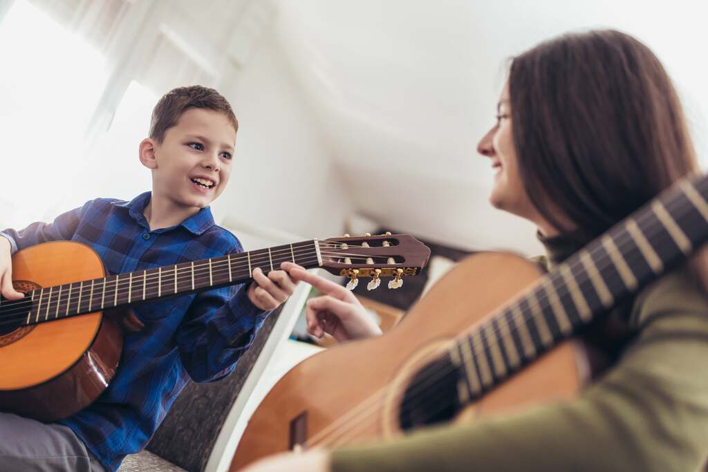 Boy playing a guitar with a music instructor