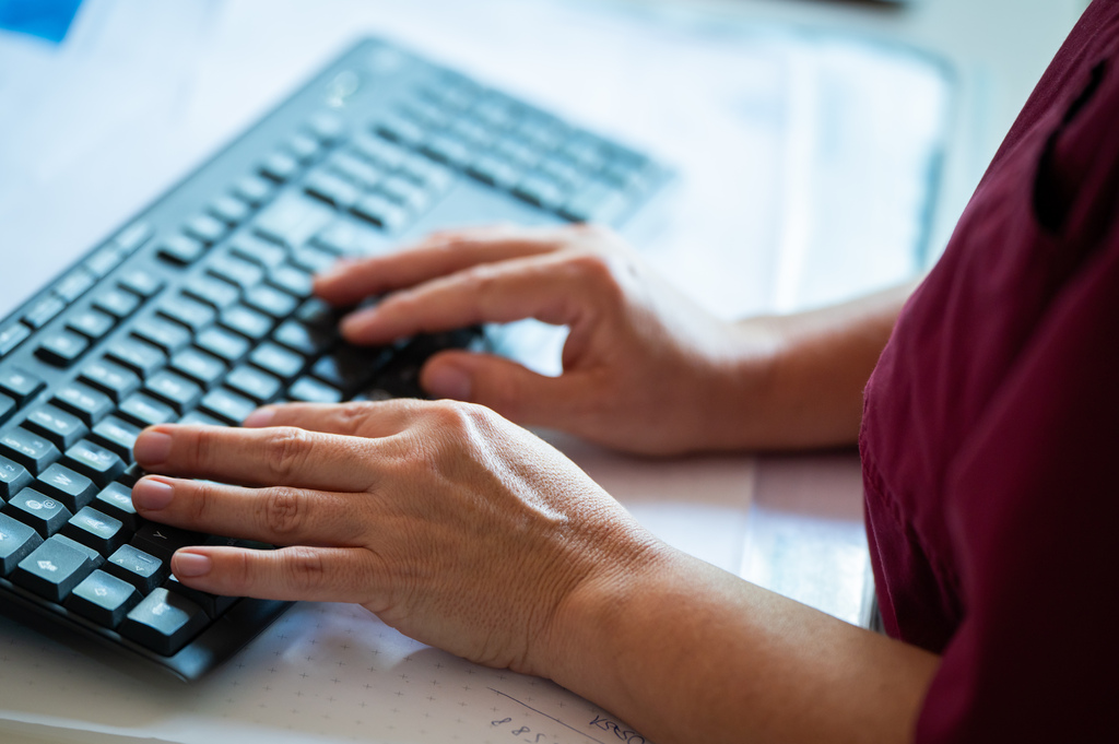 Hände auf Tastatur bei der Dokumentation