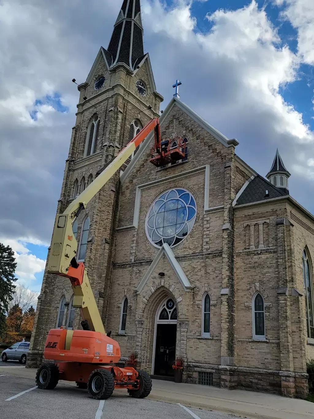 An articulating boom lift being used to repair glass in a window on a church. .
