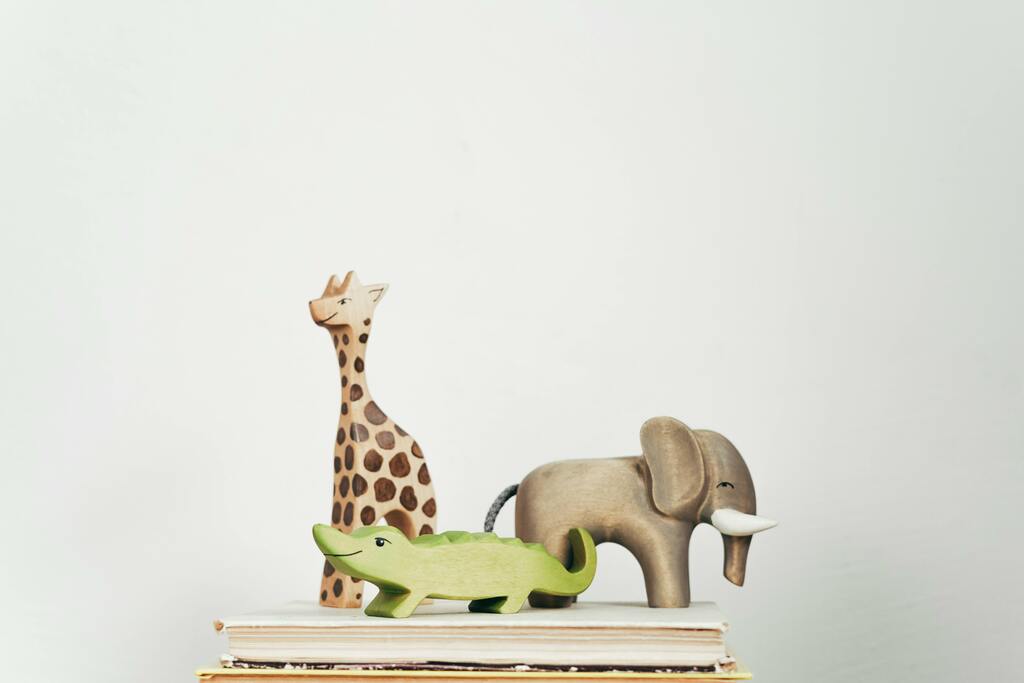 Holzfiguren von Giraffe, Elefant und Krokodil auf Büchern.