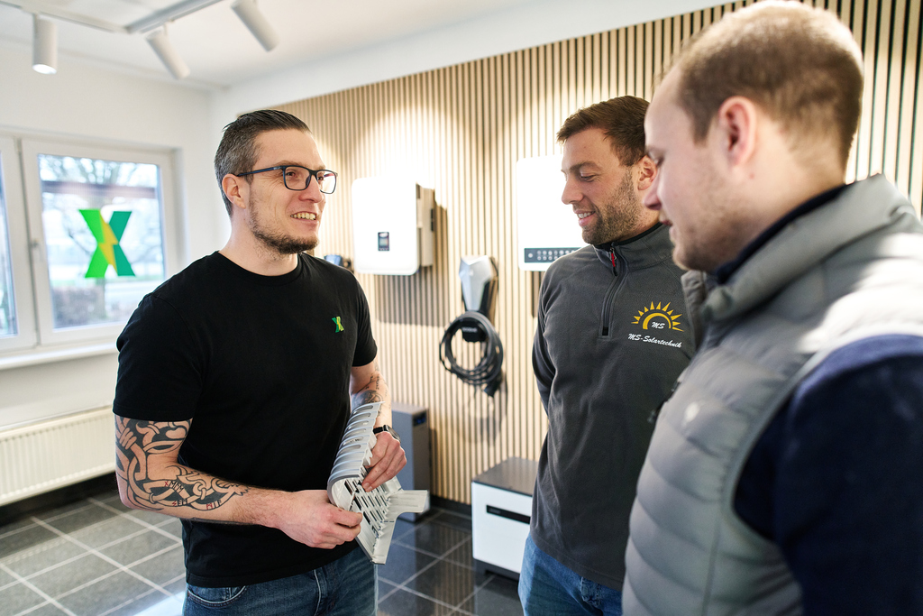 Zwei Hände halten einen Tablet-Computer, aus dem verschiedene Handwerkszeuge herausragen, dahinter ein Meesenburg-Logo