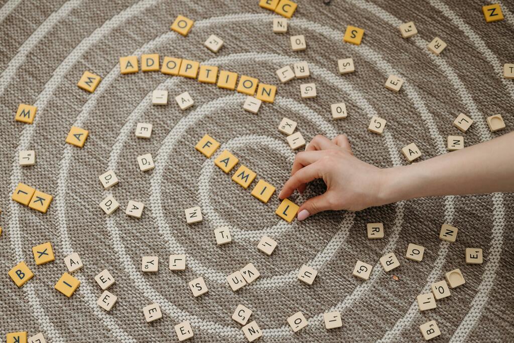Scrabble-Steine mit den Wörtern „Family“ und „Adoption“ auf Teppich