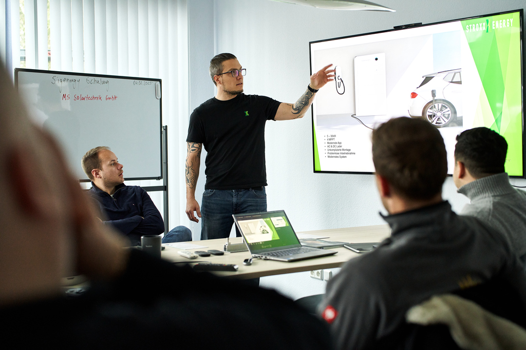 Zwei Hände halten einen Tablet-Computer, aus dem verschiedene Handwerkszeuge herausragen, dahinter ein Meesenburg-Logo